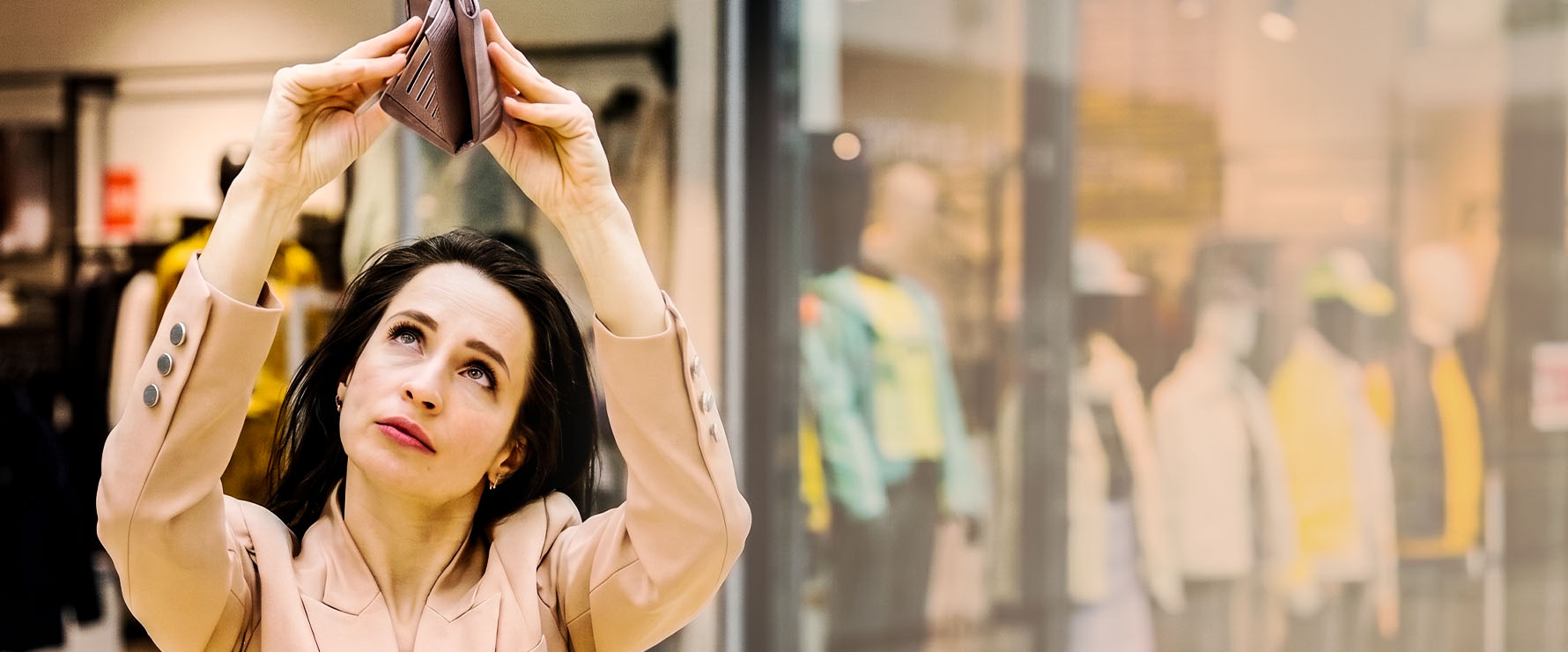 Woman in a blush blazer holding a handbag outside a fashion boutique.